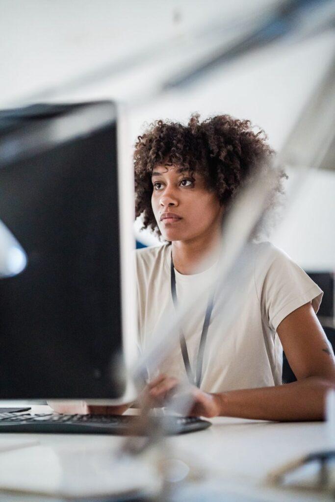 Young woman concentrating on a computer screen in a modern office setting.