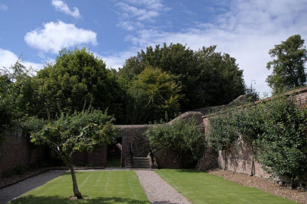 A tranquil walled garden with lush greenery and a well-kept lawn in Lisburn.