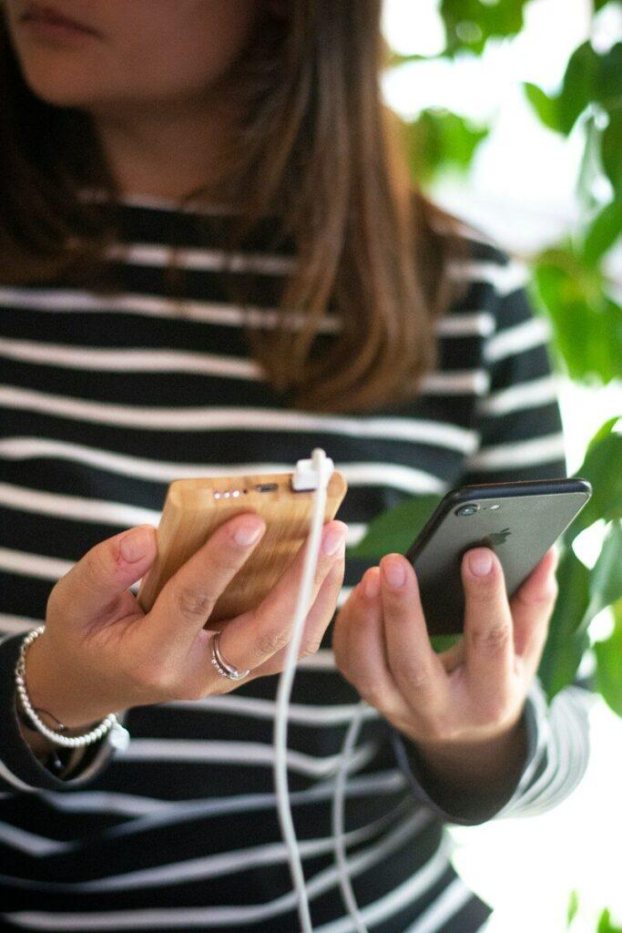 woman in black and white striped long sleeve shirt holding silver iphone 6