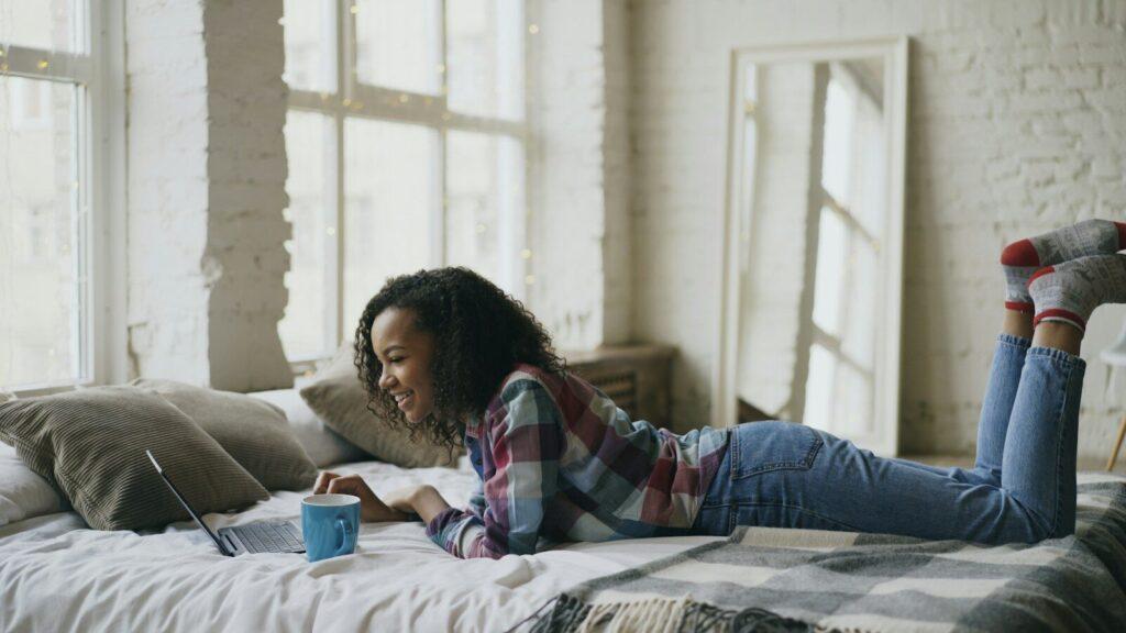 Young woman working on laptop in bed